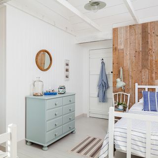 bedroom with white wooden bed white wooden walls and wooden flooring