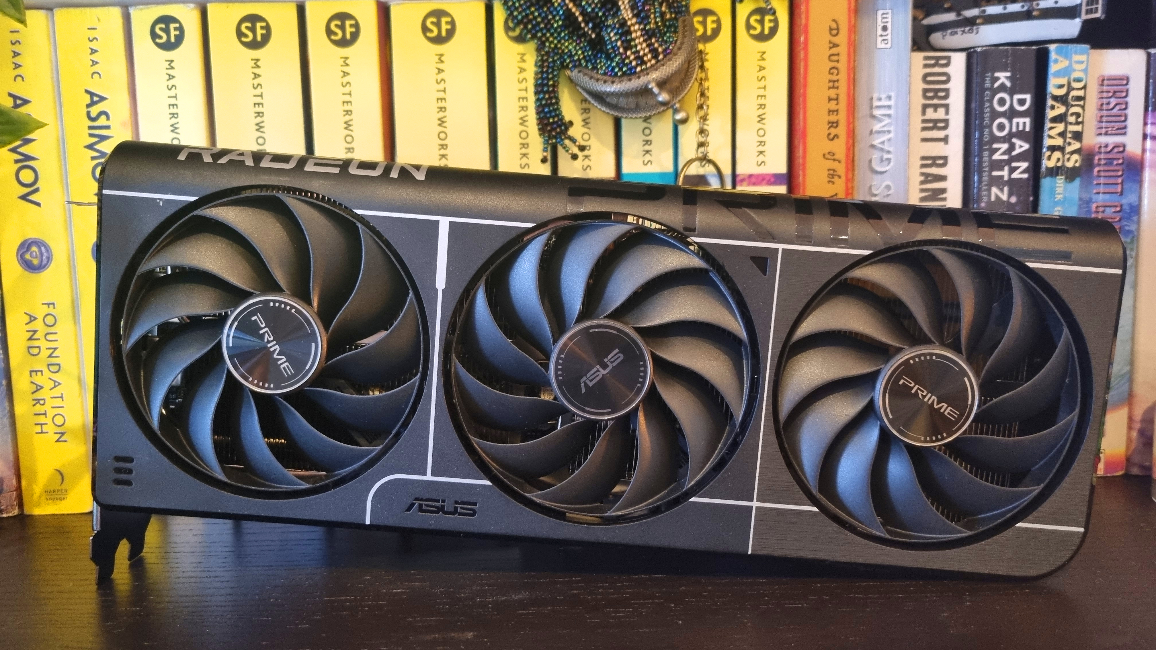 An Asus Prime Radeon RX 9060 XT 8 GB graphics card in front of some books on a bookshelf