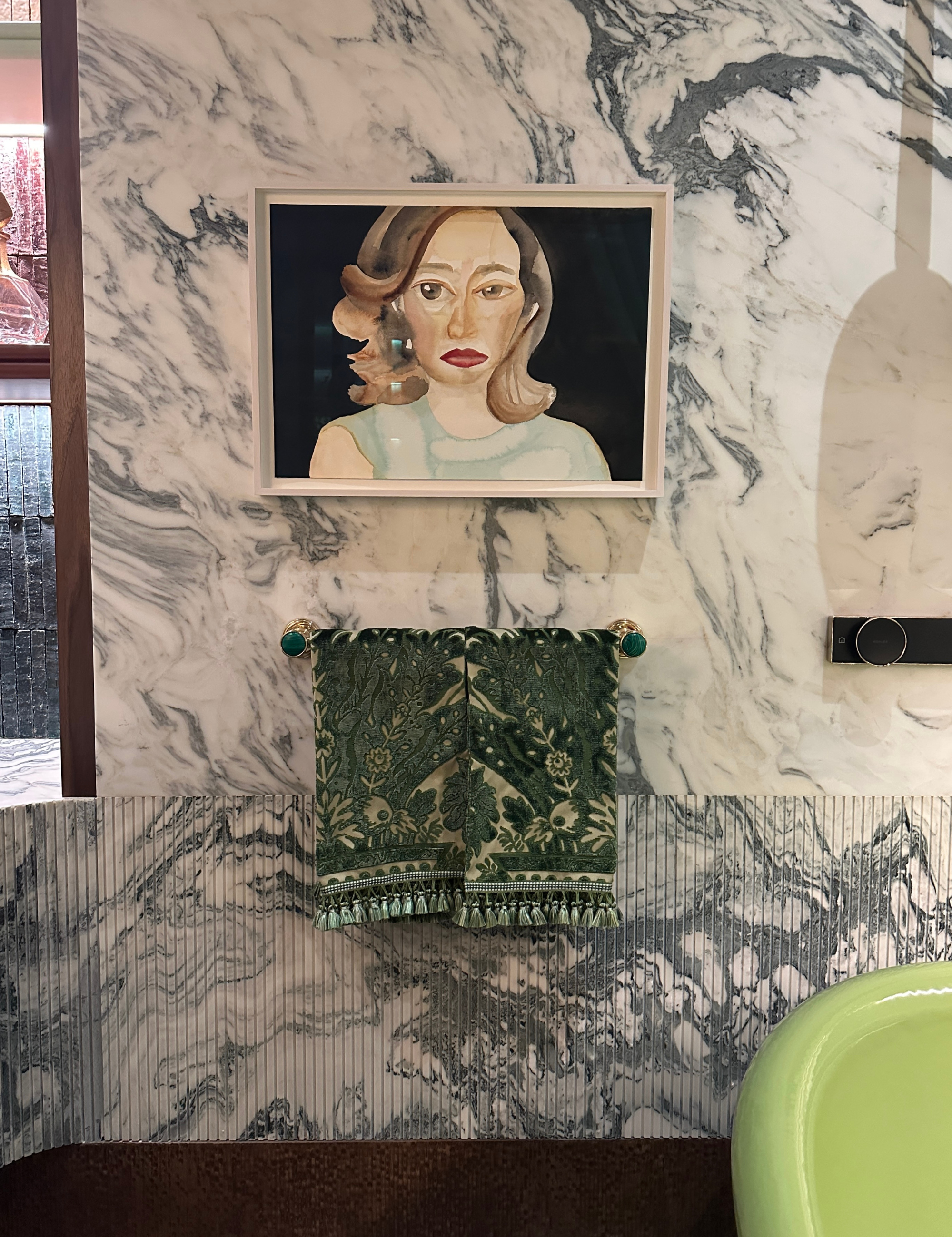 Marble-drenched bathroom featuring a contemporary portrait of a lady accented by green jacquard hand towels