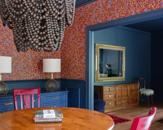 A hague blue farrow and ball painted dining room with a red pattered wallpaper