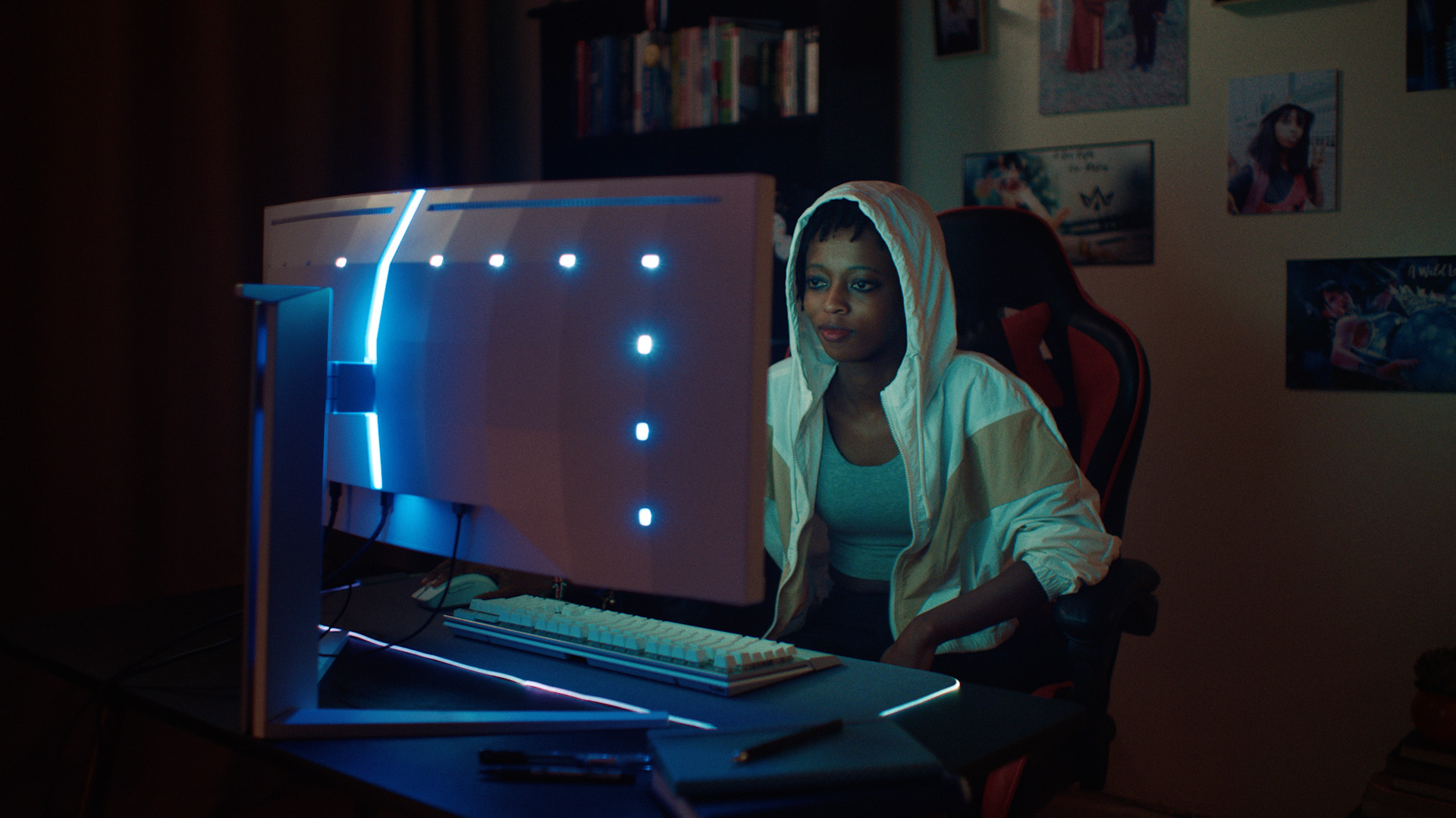 A black woman sits in front of an Evnia monitor playing games