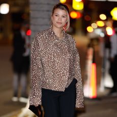Sofia Richie walks down the street wearing black trousers with snakeskin heels and a deer print jacket.