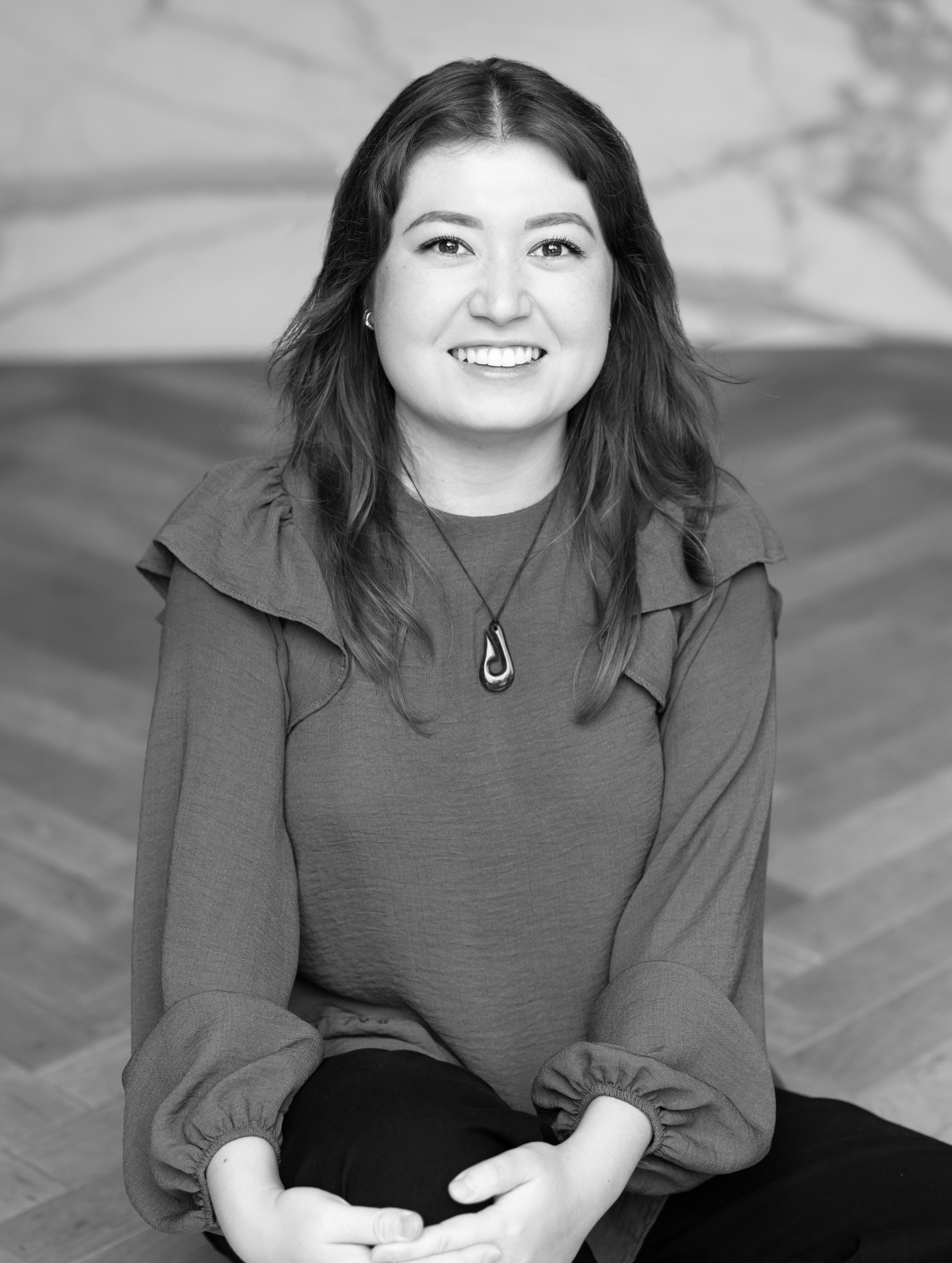 A black and white picture of a woman with mid-length dark hair smiling at the camera