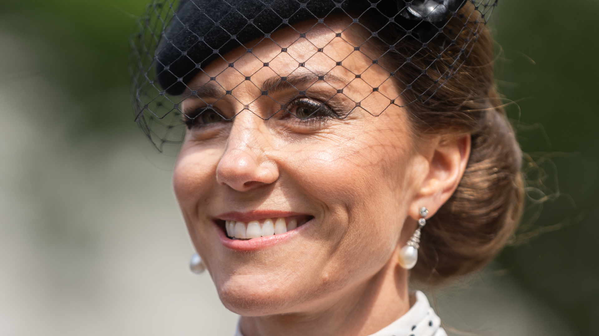 Kate Middleton wearing a white polka dot dress and black hat with a veil