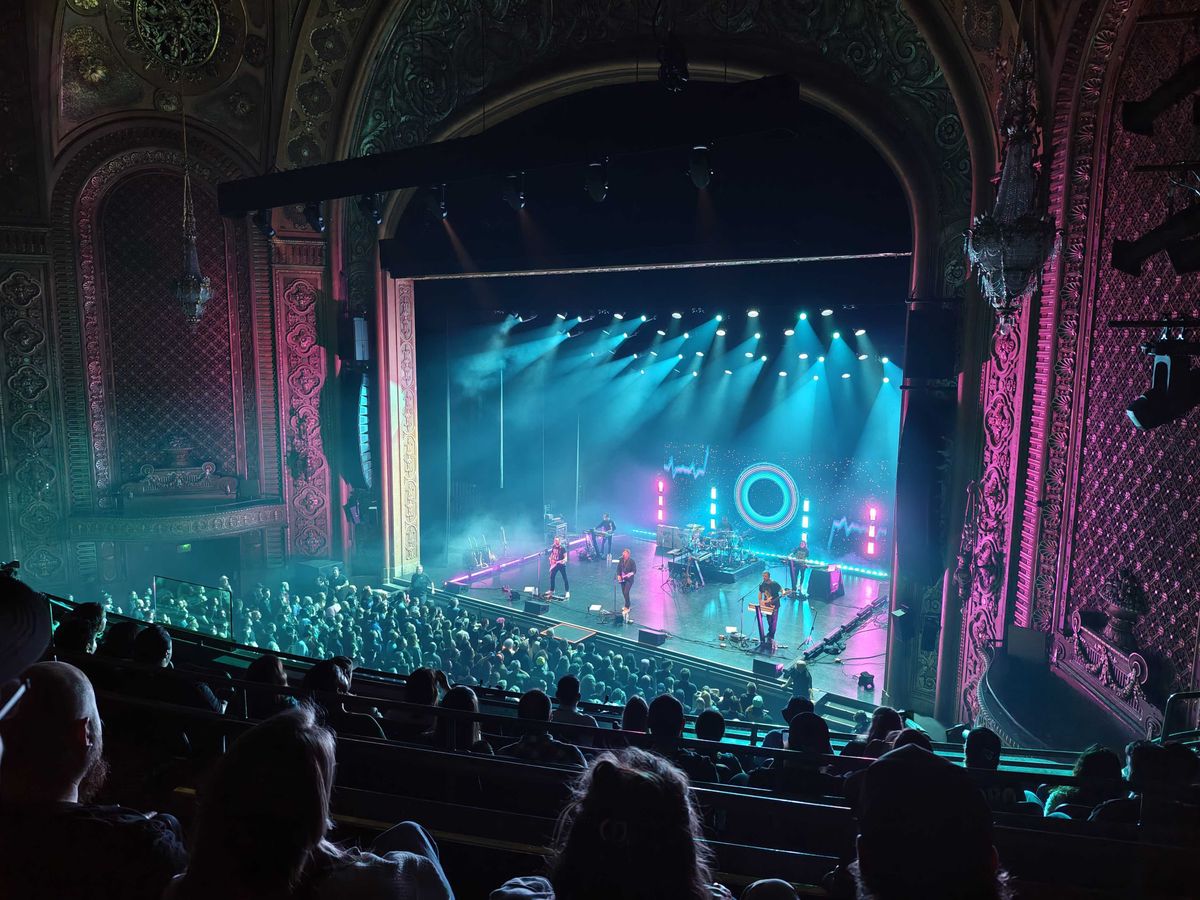 A band performing in a dark theater with the stage brightly lit