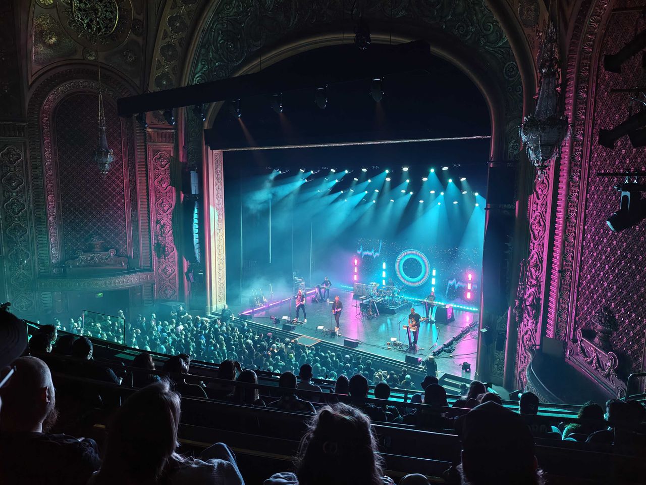 A band performing in a dark theater with the stage brightly lit