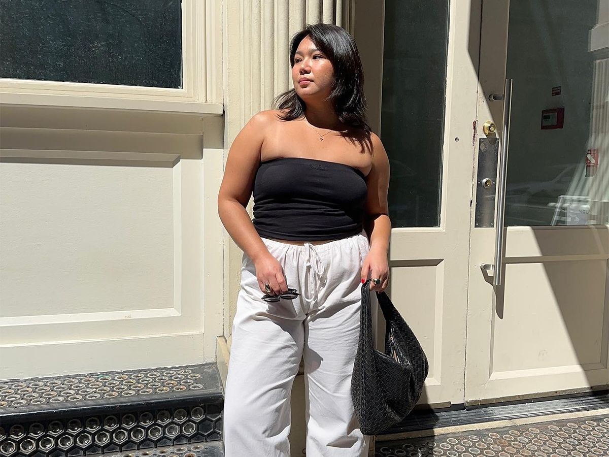 Influencer Marina Torres wears white linen trouser, a black tube top, and a woven black hobo bag.