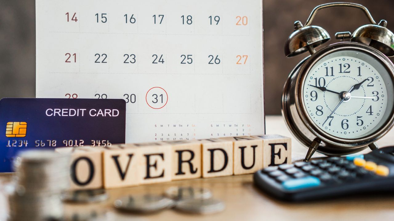 Overdue credit card payment concept with credit card, calendar reminder, clock, calculator, and blocks reading &quot;Overdue&quot; sitting on a desk