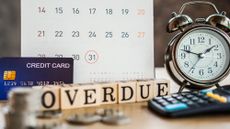 Overdue credit card payment concept with credit card, calendar reminder, clock, calculator, and blocks reading "Overdue" sitting on a desk