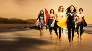 Huvudpersonerna i serien Surviving Summer går på stranden med hvert sitt surfebrett under armen.