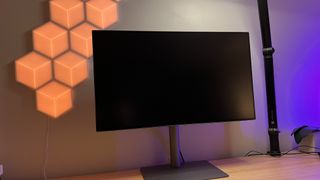 BenQ PD3220U Monitor on a wooden desk in front of some LED lighting