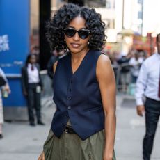 Ayo Ediberi wearing a navy blue vest and green cargo pants