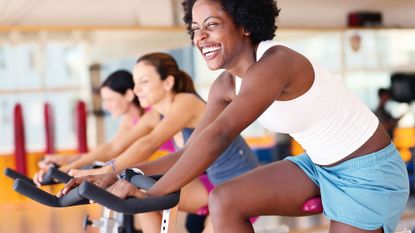Women in the gym on stationary bikes enjoying the exercise bike benefits