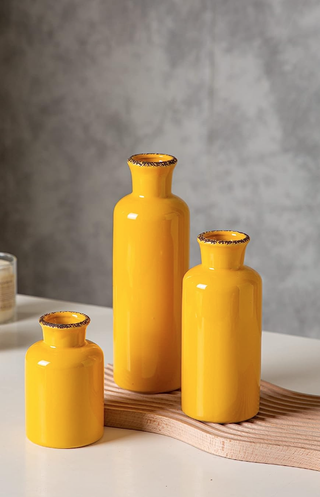 three yellow vases sit on a wavy wooden tray