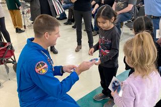 Canadian Space Agency astronaut Jeremy Hansen gives out decals of his new Artemis II personal patch to young fans at a Feb. 8, 2024 event at First Nations University of Canada.