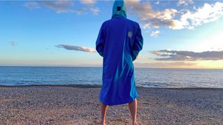 Man on beach wearing White Water Softshell Robe (showing the back)