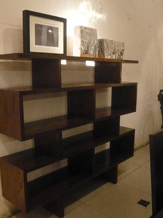 Dark wooden shelving unit with a framed picture and two ornaments on the top shelf