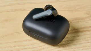 A photo of a single EarFun Air Pro 4 earbud resting on the case, on a wooden surface