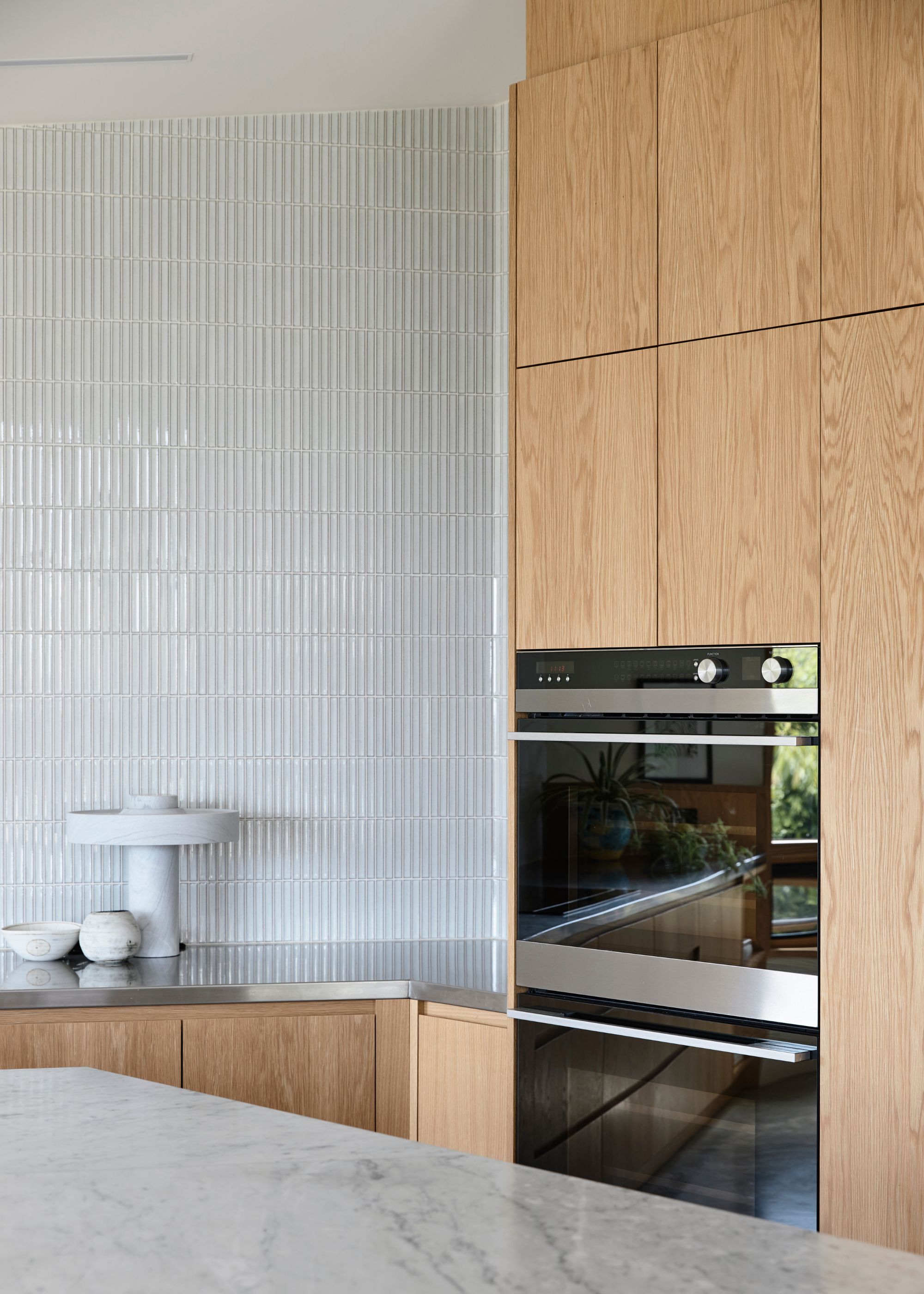 A kitchen with an oven and a microwave as well as a view of the counter with a kitchen bowl and decor pieces