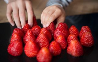Children reaching for strawberries on a table