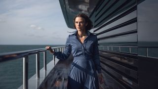 Keira Knightley walking on a yacht in a blue pleated dress