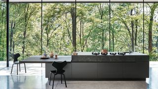 modern kitchen with floor to ceiling black framed windows, central black kitchen island with integrated cooking burners and seating area to side with two black chairs