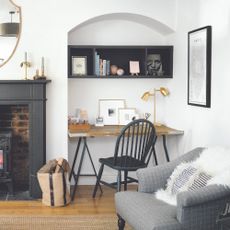 A living room painted in white with an alcove used for a home office set-up with a desk