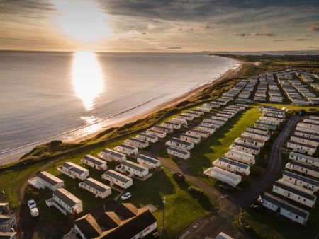 a row of caravans opposite a beach during sunset