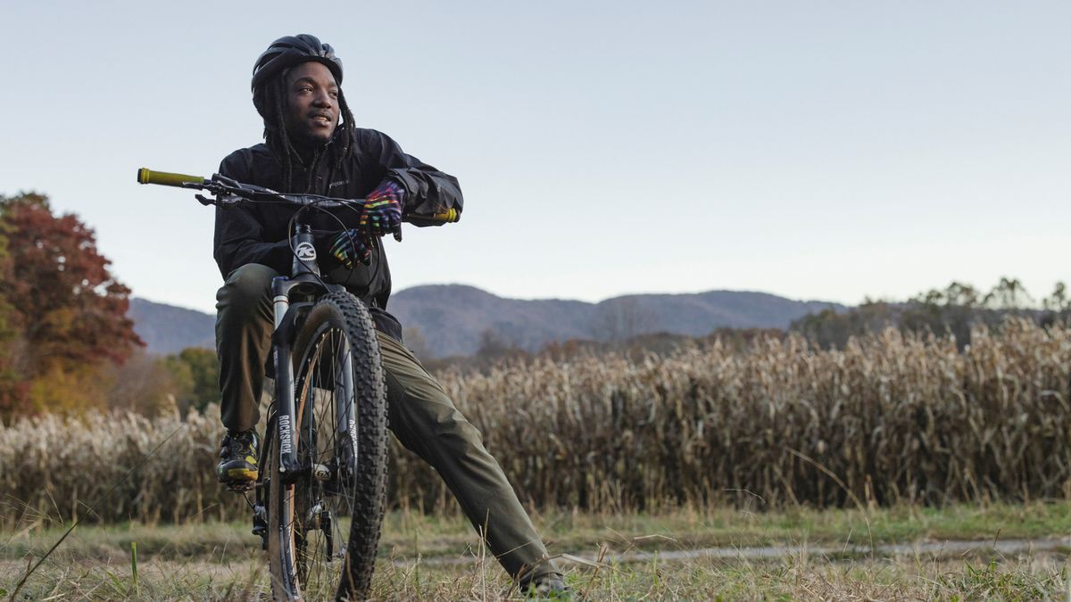 A young man straddling a mountain bike in the countryside