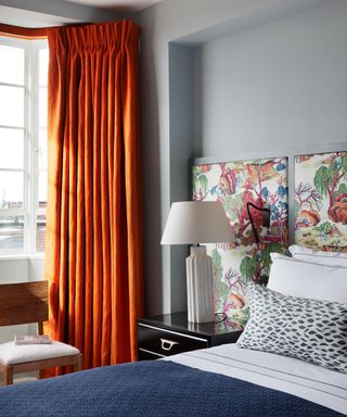 Grey bedroom with orange curtains and blue bed linen