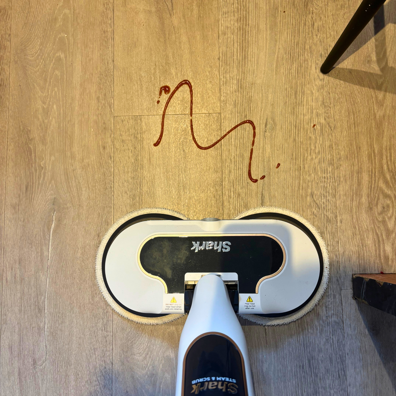 Shark Steam &amp; Scrub Automatic positioned in front of smeared tomato ketchup on laminate flooring