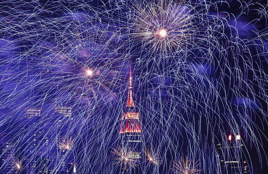 TOPSHOT - Fireworks burst over the New York skyline, the Empire State Building lit in red and gold in honor of the Chinese Lunar New Year, as seen from Weehawken, New Jersey, on February 6, 2016.