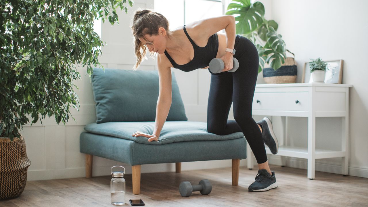 Woman exercising with dumbbell in domestic setting