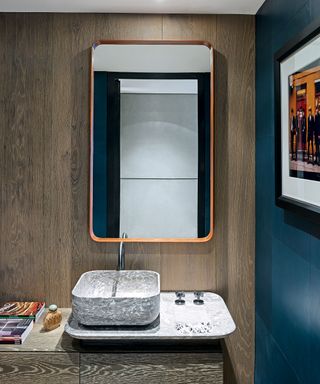 A mid-century modern cloakroom with wood panels and a rectangular mirror