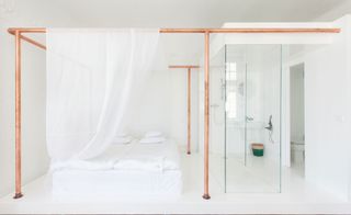 Bright white guestroom with copper poles