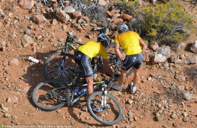 Team FedGroup Itec's Brandon Stewart (left) helps teammate Konny Looser repair his rear wheel after a crash early on during stage 3