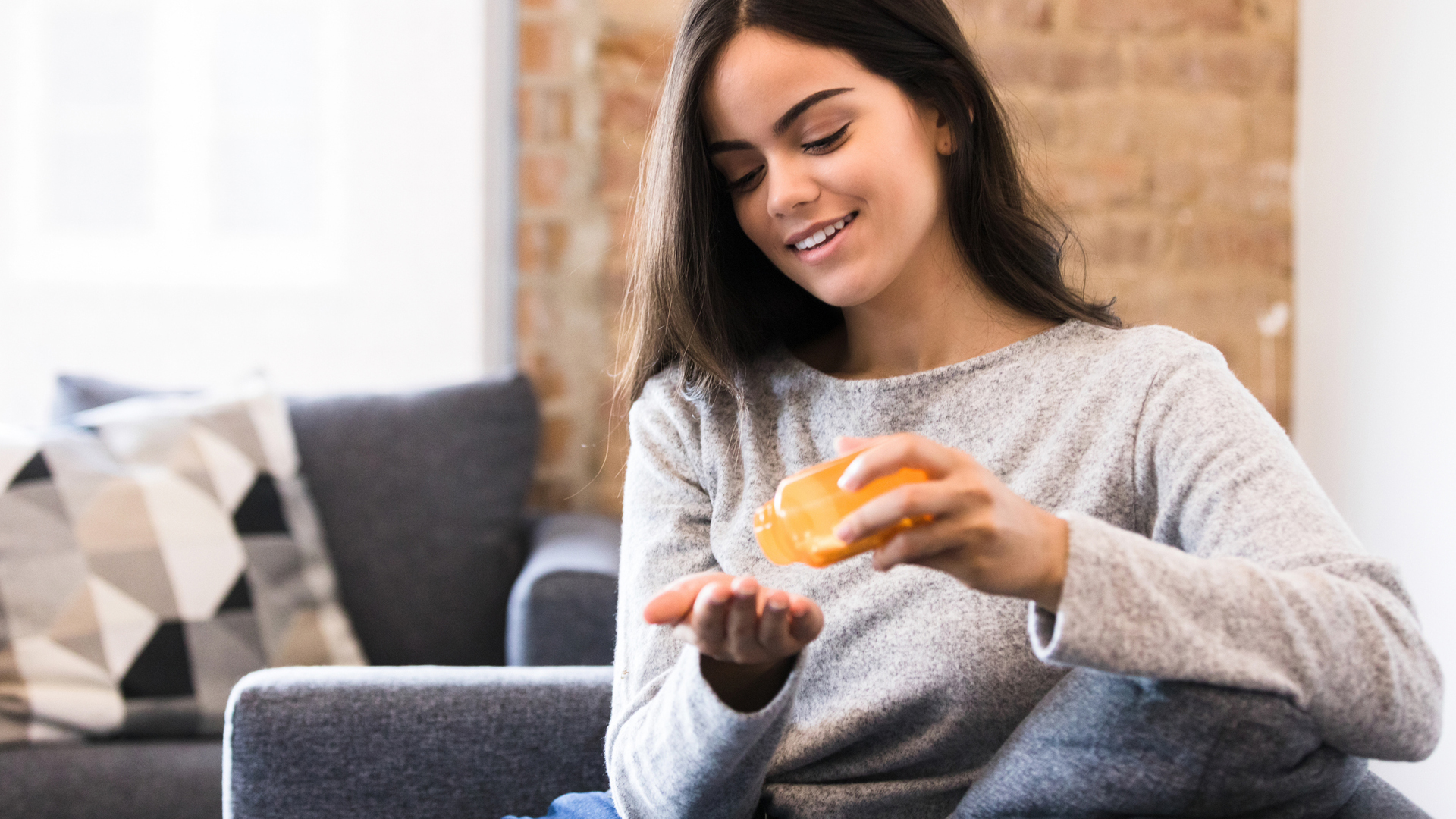 woman sat on her couch taking a magnesium supplement