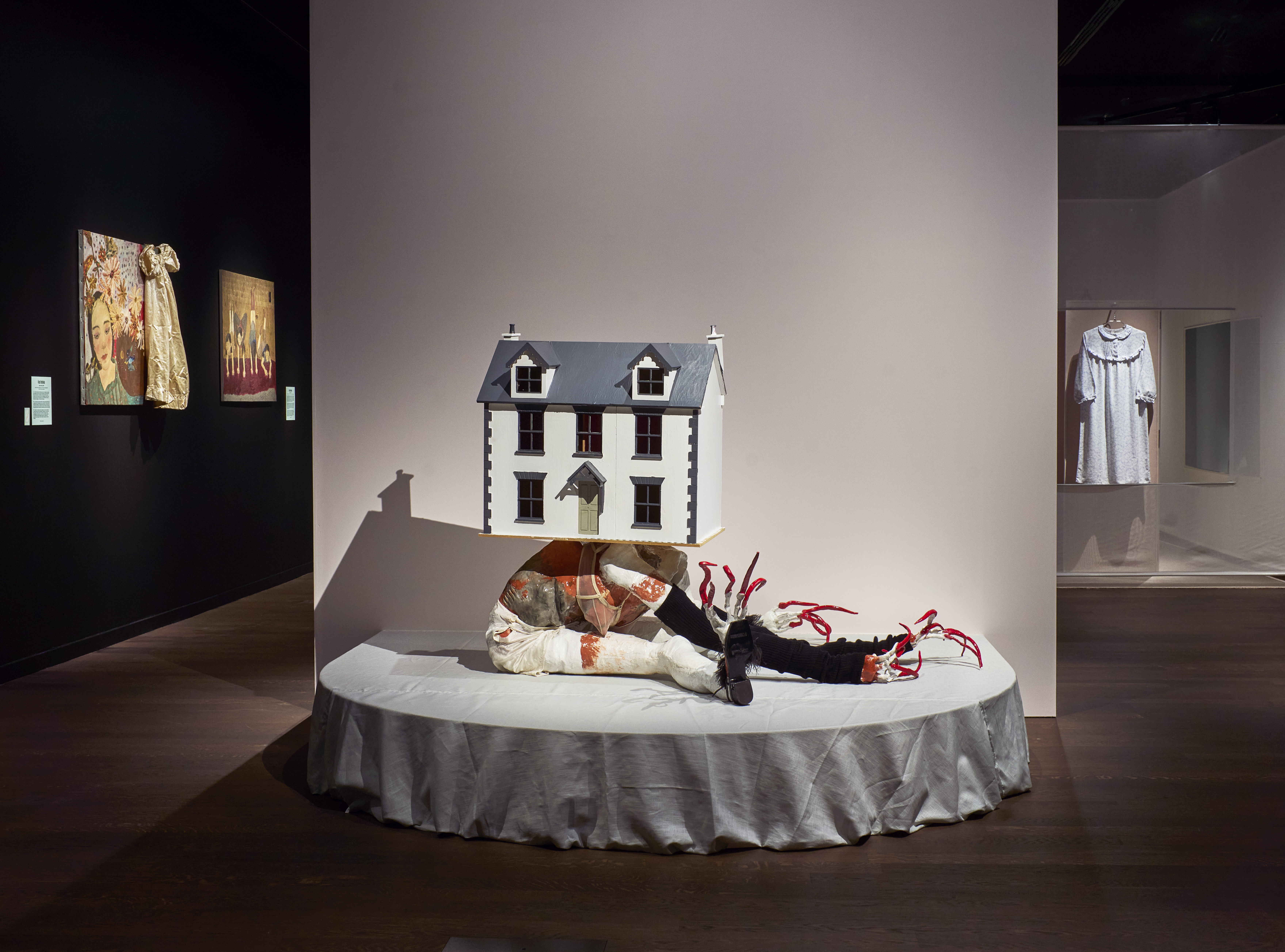 a sculpture of a white house on top of a contorted body at a museum exhibit for girls on boredum rebellion and being in between at momu antwerp