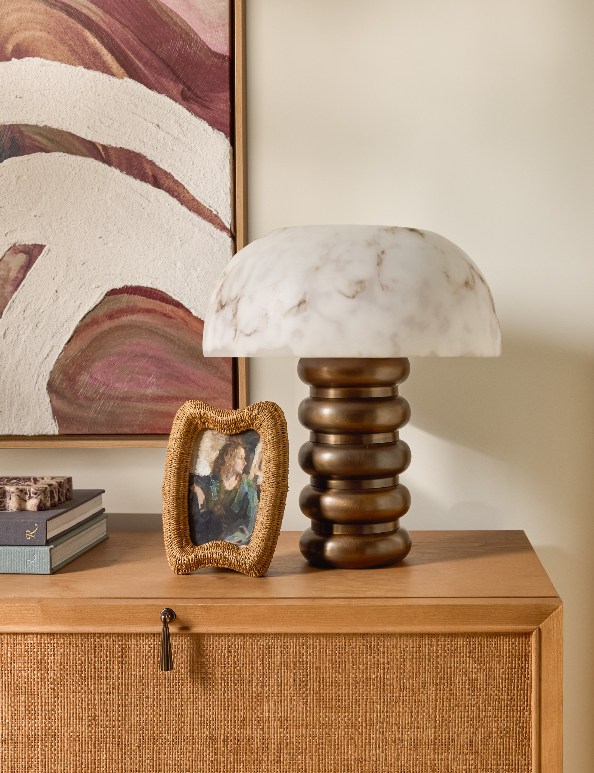 Lulu and Georgia rattan photo frame pictured alongside a bronze-based, marble-shaded table lamp from the brand's fall 2025 collection