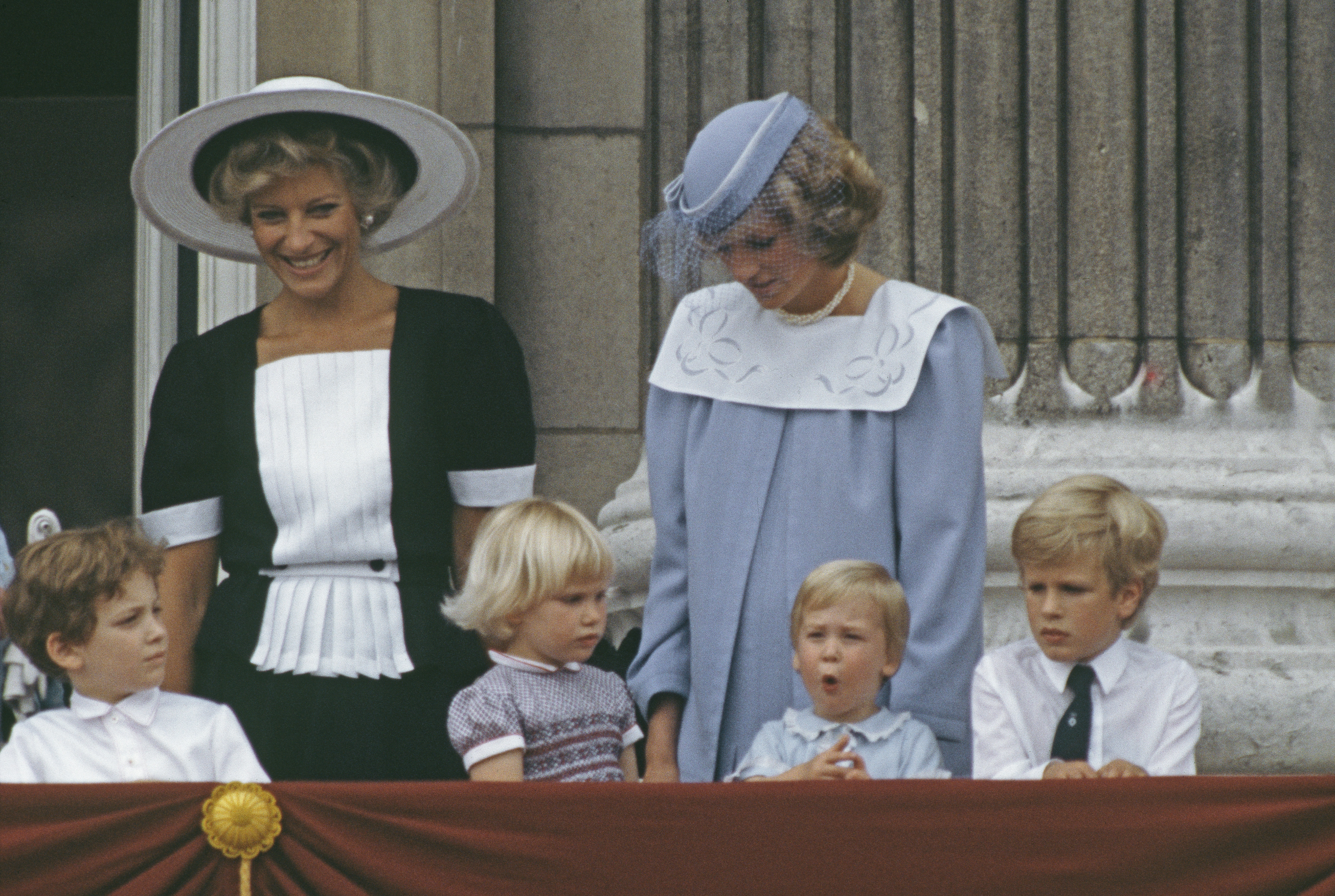 Princess Michael of Kent wears a black and white dress and stands next to Princess Diana, who is wearing a baby blue sailor dress on the Buckingham Palace balcony in June 1984