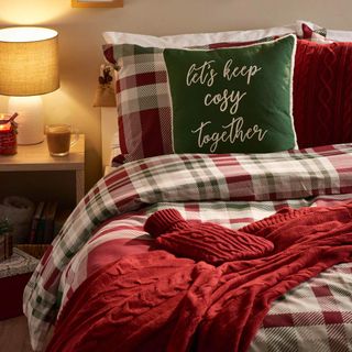 Christmas bedroom with tartan bedding and festive cushion