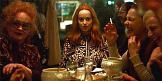 Dakota Johnson Suspiria at a table with drinks and witches