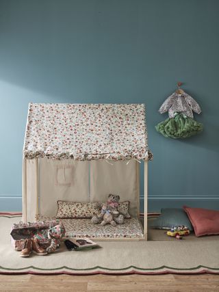 teal nursery with Liberty Fabric Wendy house, play mat underneath, clothes hanging up, toys