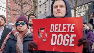 Protester holding a delete doge sign