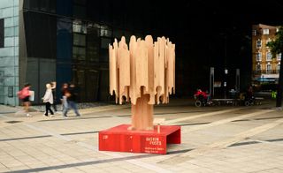 Tree-shaped wooden designpost on red plinth