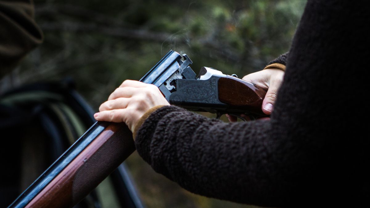 A person unloading a hunting shotgun