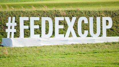 The word #fedexcup as a large sign near a grass bank
