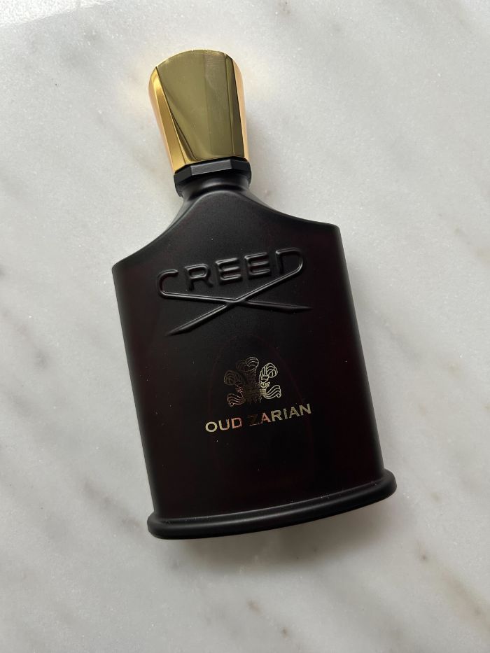 A picture of a Creed perfume on a marble background