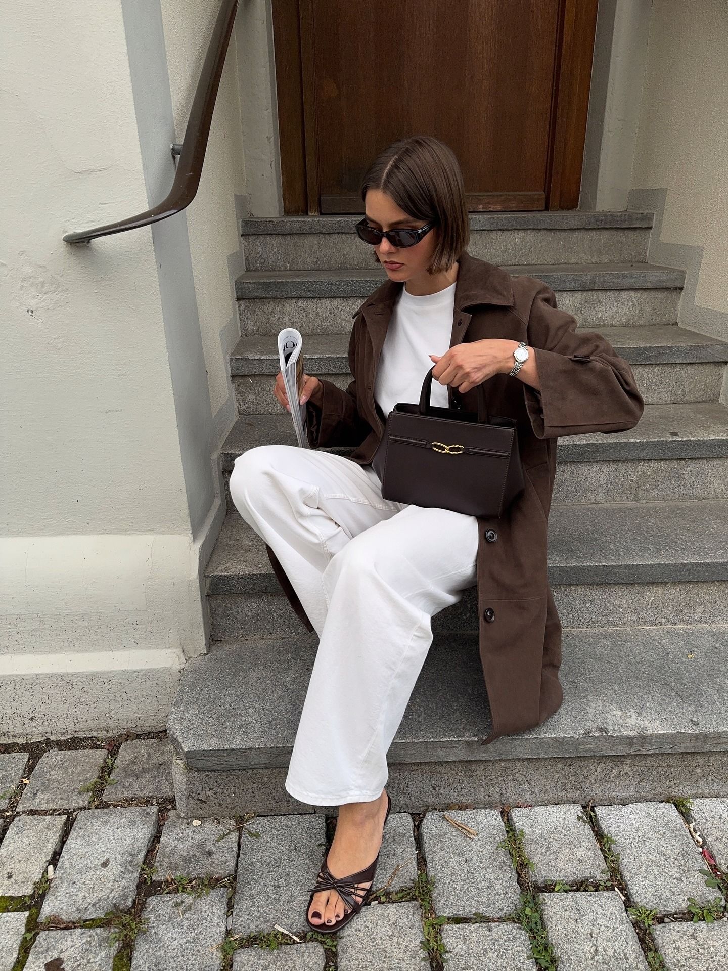 Influencer @maryljean wears white jeans with a brown jacket and chocolate brown heels.