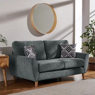 Green sofa underneath a round mirror